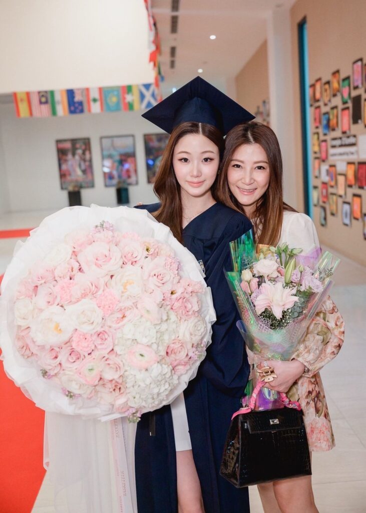 Graduate holding a large pink bouquet from Flowers by Basketeer with a family member