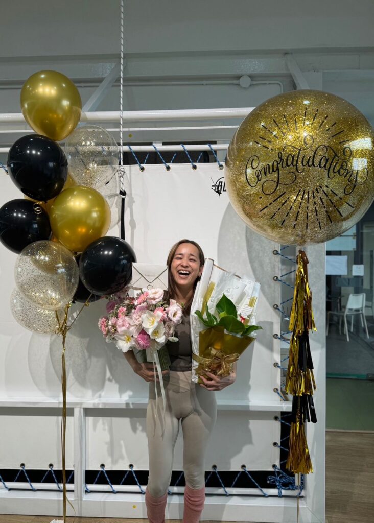 Woman celebrating with pink bouquet and balloons from Flowers by Basketeer