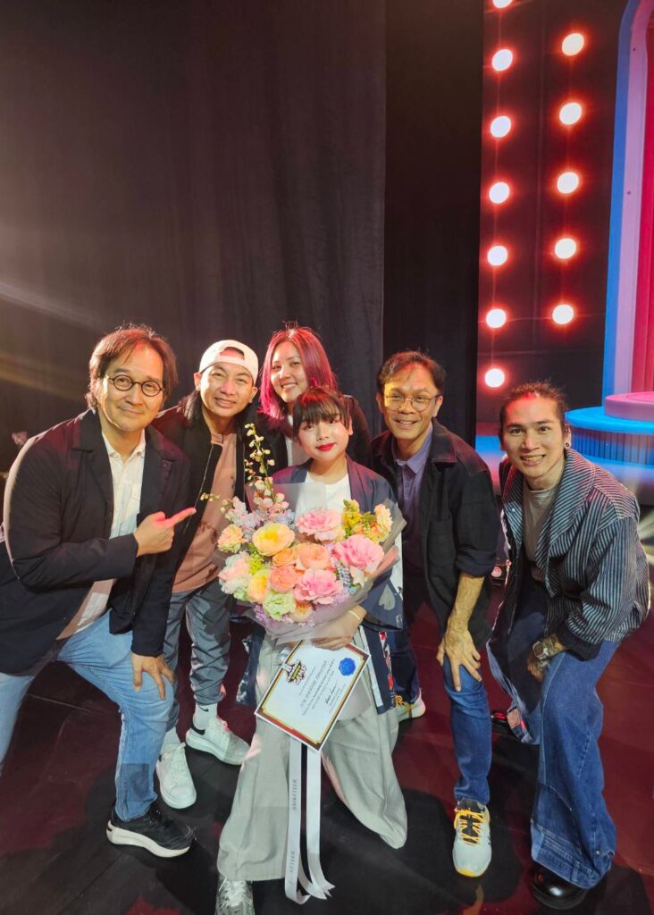Performer holding a colorful bouquet from Flowers by Basketeer surrounded by friends