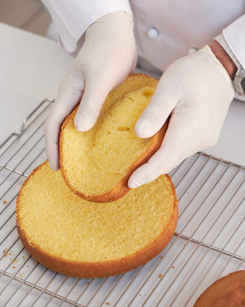 Baker inspecting sponge cake texture before assembling Victoria sponge at Charlotte Bakery Bangkok