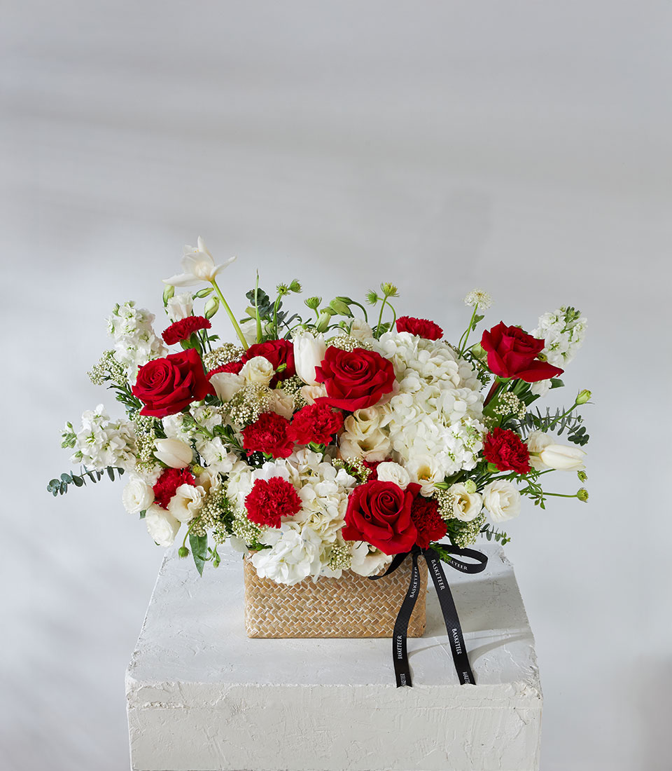 Full view of red and white flower basket with imported Explorer Roses, hydrangeas, and tulips tied with black satin ribbon.