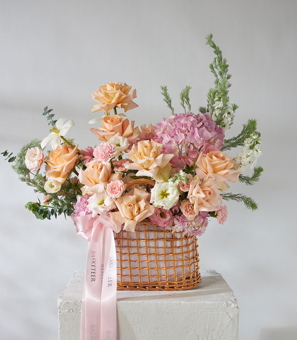 Full view of peach and pink flower basket with imported Tiffany Roses and pink hydrangeas in woven basket.