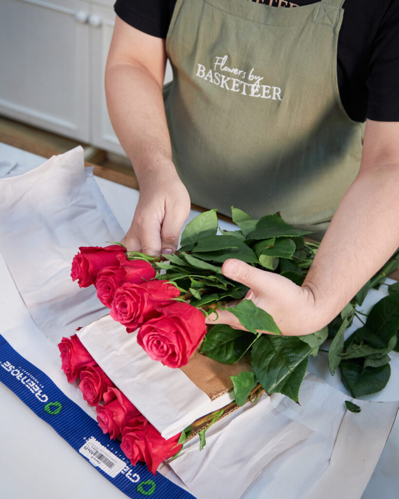 Florist from Flowers by Basketeer preparing fresh red roses for arrangement