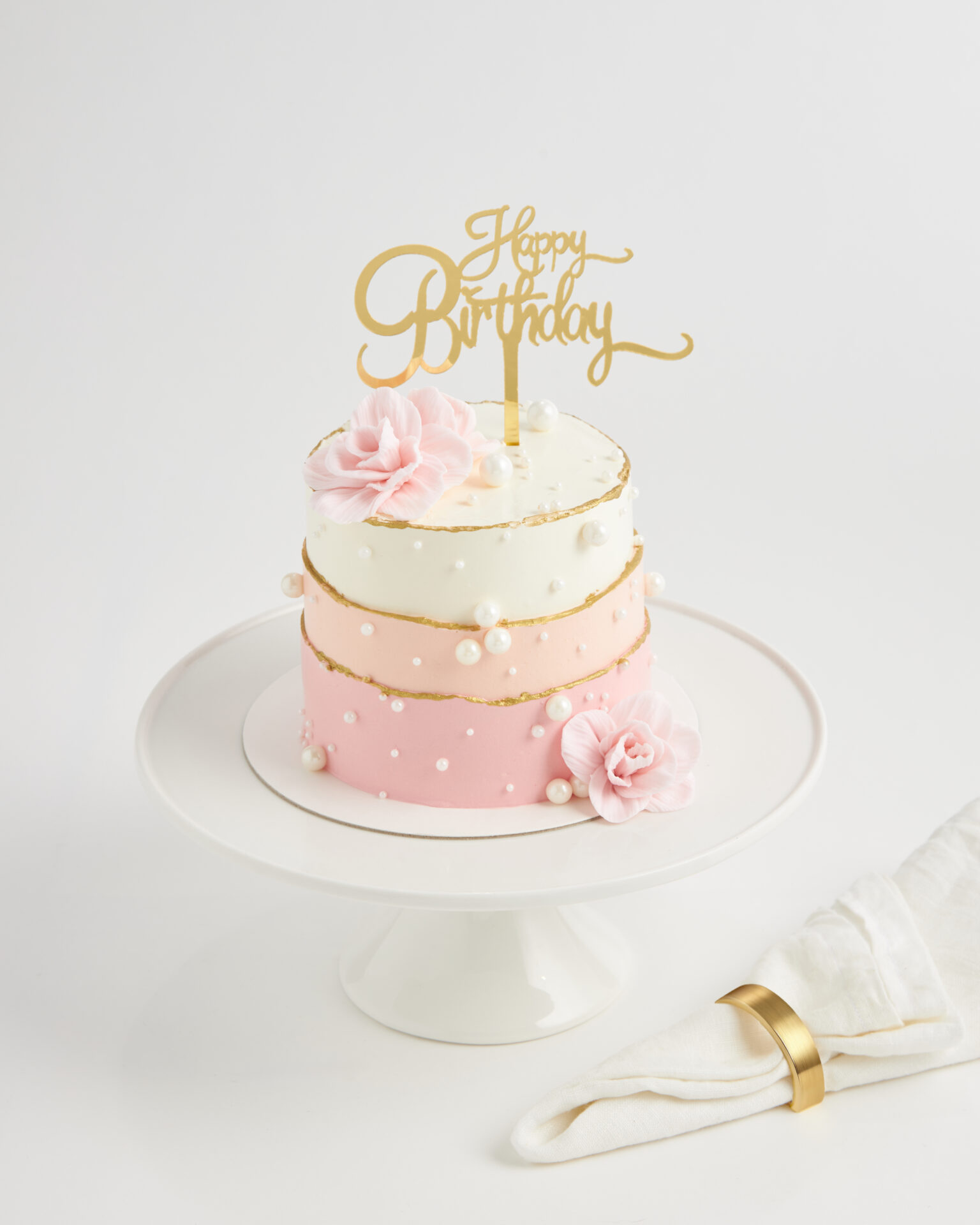 Two-tier pink and white birthday cake with pearl decorations and gold topper, Charlotte Bakery Bangkok