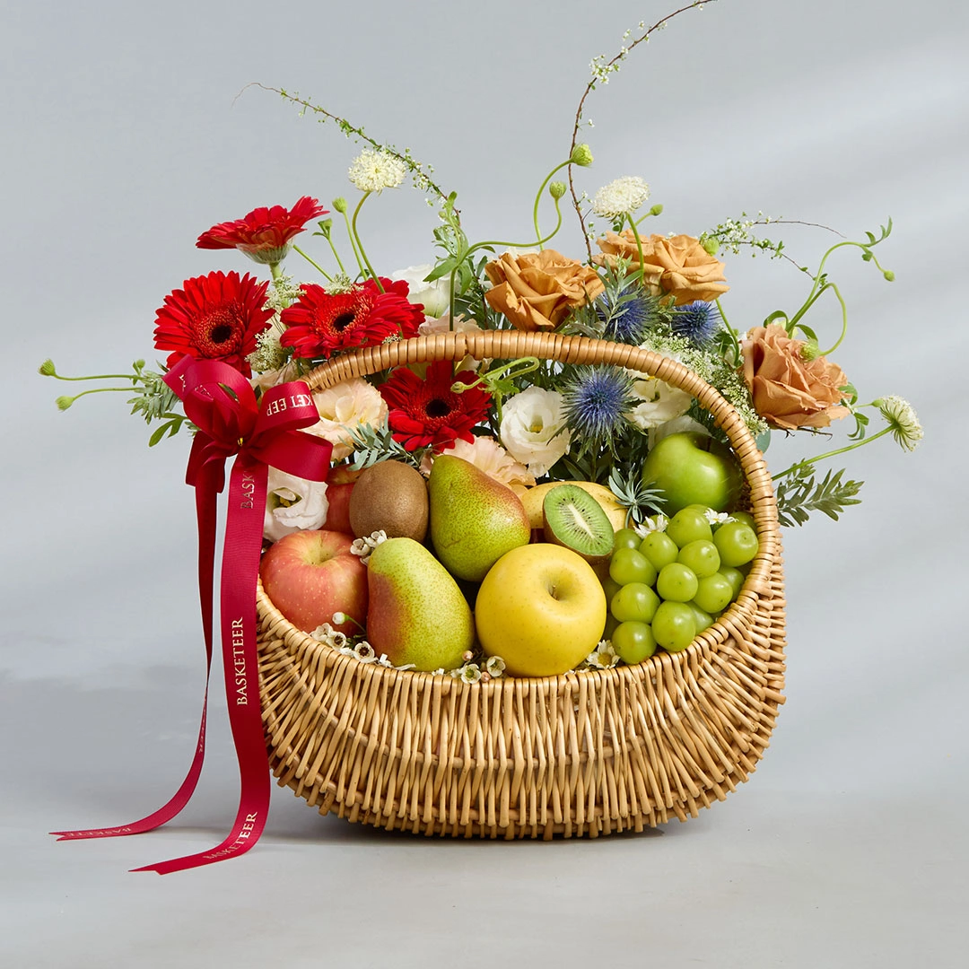 Fruit gift basket with imported apples, pears, and grapes, beautifully decorated with fresh flowers and red Basketeer ribbon