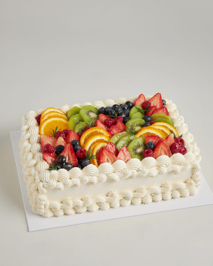 A classic rectangular cake with silky white icing, crowned with fresh fruit, crafted in Bangkok by Charlotte Bakery’s skilled hands.