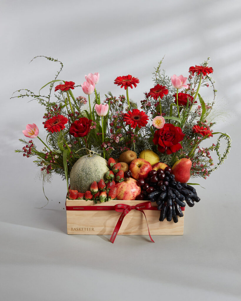 Luxury fruit basket with fresh fruits and red floral arrangement by Basketeer Bangkok.