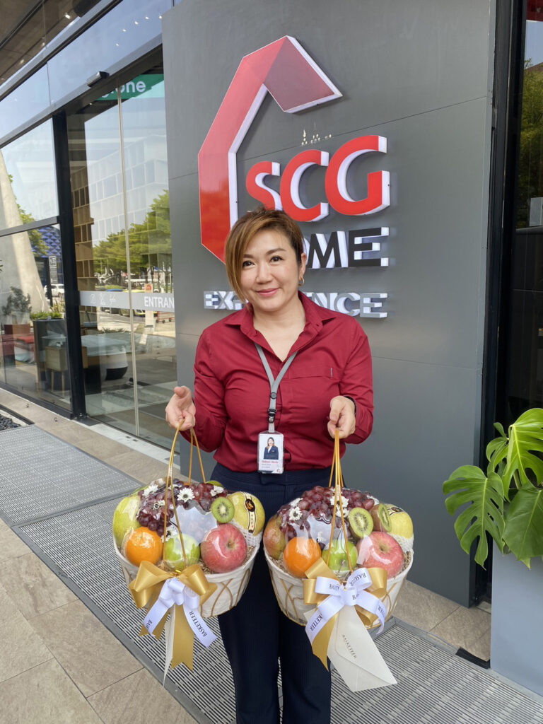 Customer holding two Basketeer premium fruit baskets in front of SCG Home office.