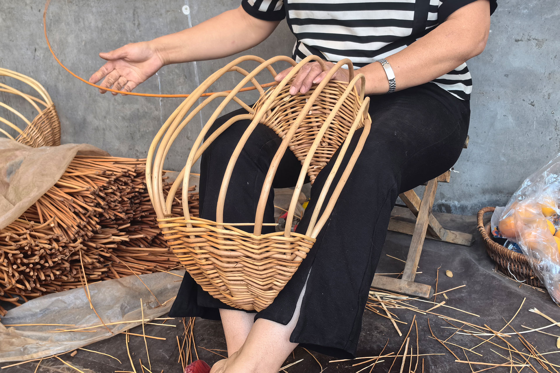 A person wearing a hairnet and mask examines a printed sheet of black-and-white film negatives while sitting at a desk, with the same image displayed on a computer monitor.
