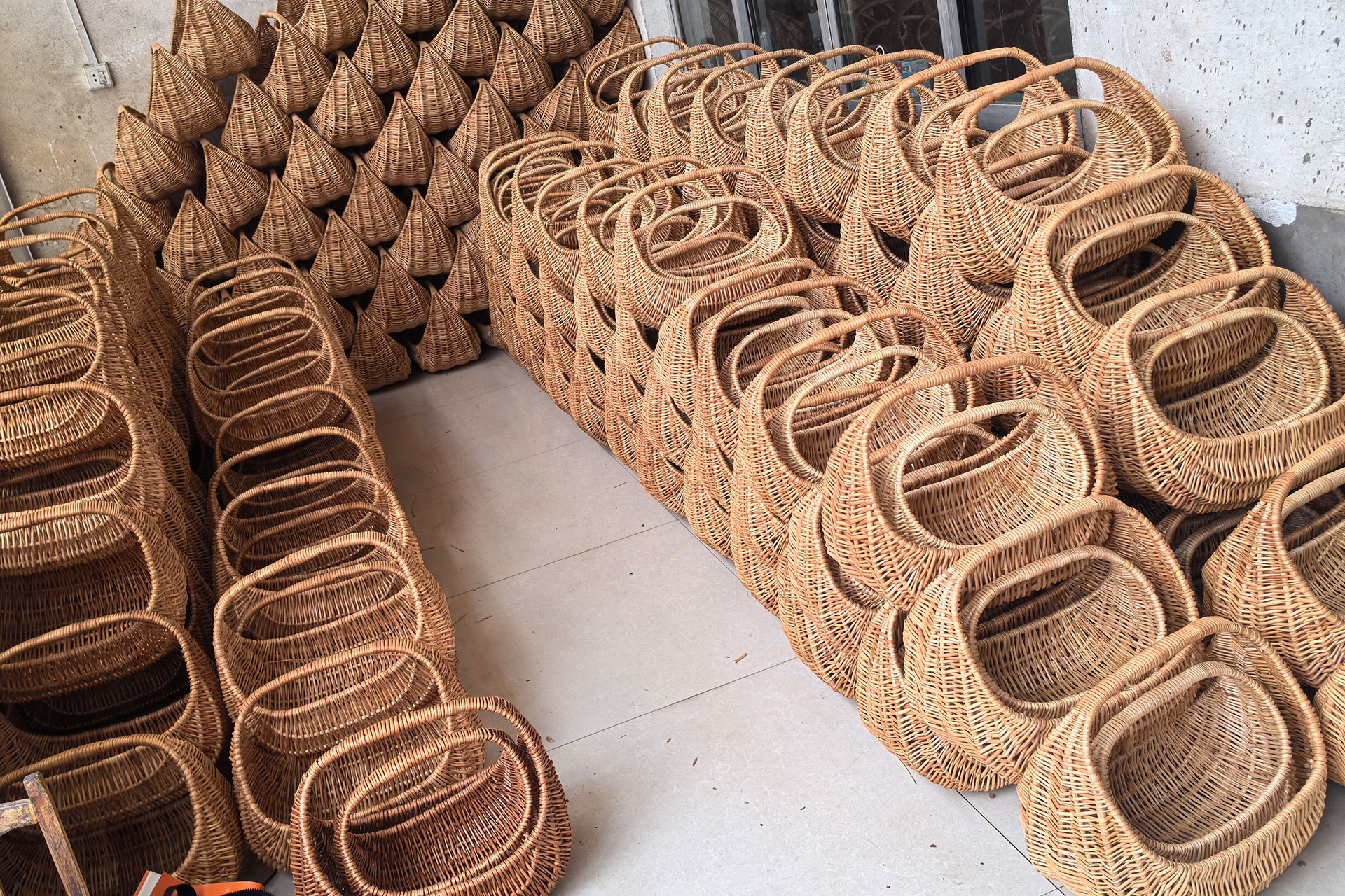 A pastry chef in a white coat and black gloves decorates a red sports car-shaped cake, focusing intently as he adds details. Another chef works in the background with a similar cake.