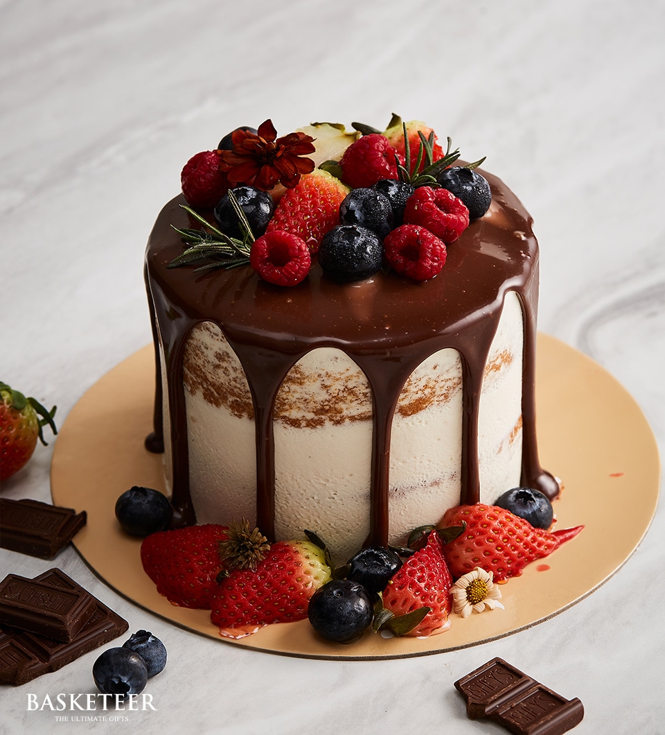 Charlotte Bakery chocolate drip cake topped with fresh strawberries, raspberries, and blueberries.