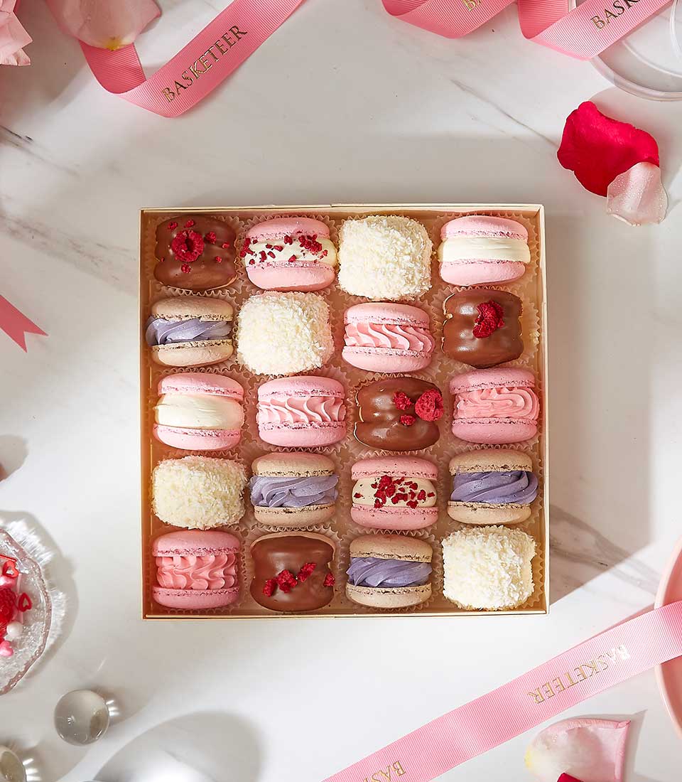 A Charlotte Bakery macaron gift box filled with pink, lilac, chocolate, and coconut-style macarons.