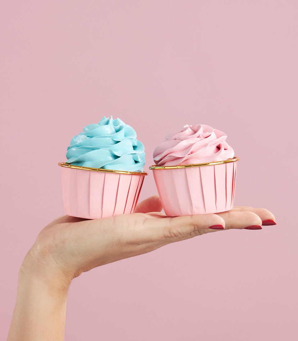 Charlotte Bakery blue and pink buttercream cupcakes held gently in hand.