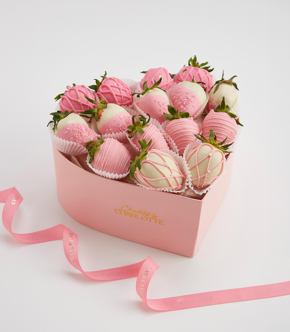 Pink and white chocolate-covered strawberries arranged in a heart-shaped Charlotte Bakery gift box.