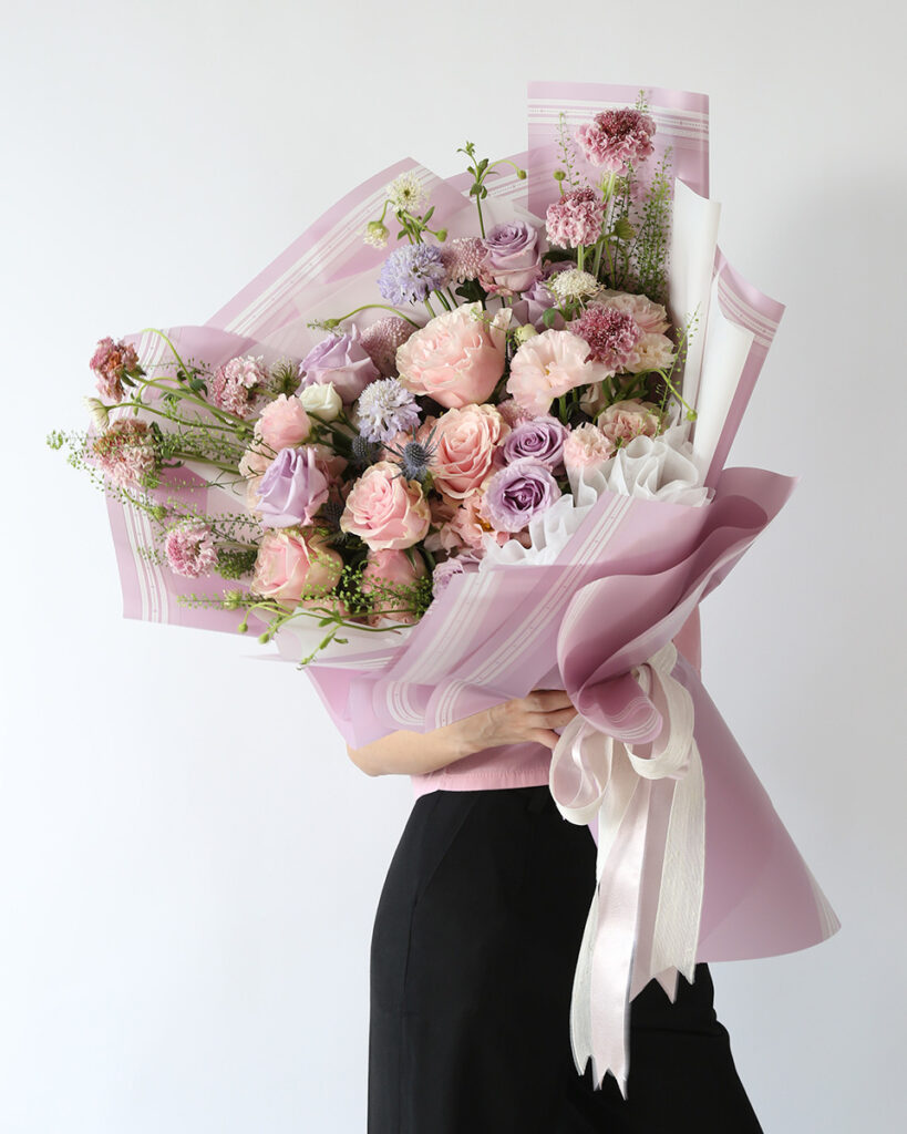 Elegant lavender and pastel pink bouquet featuring Ocean Song roses and premium blooms by Flowers by Basketeer.
