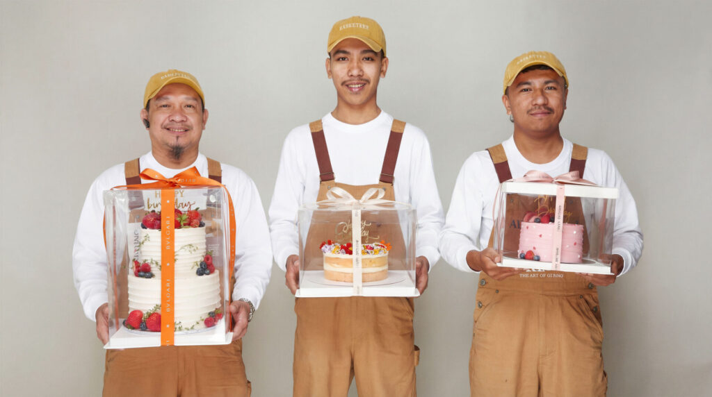 Professional Charlotte Bakery delivery team members holding premium cakes in clear boxes, demonstrating safe and careful cake delivery services in Bangkok.