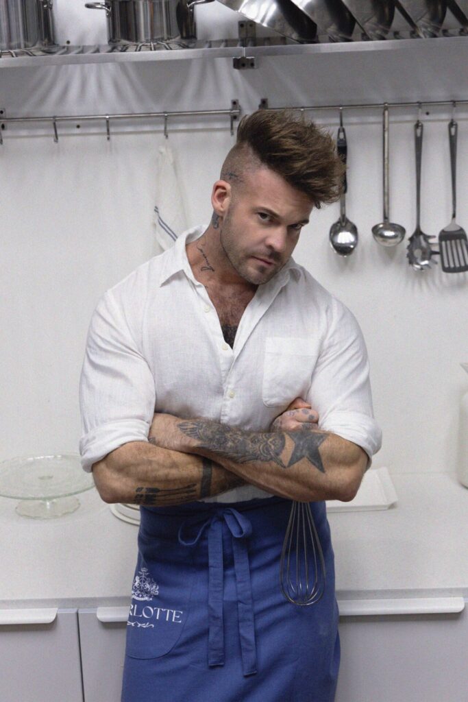 Charlotte Bakery founder Chef Dan Stoner in the commercial kitchen, assembling a layer cake and inspecting sponge quality.