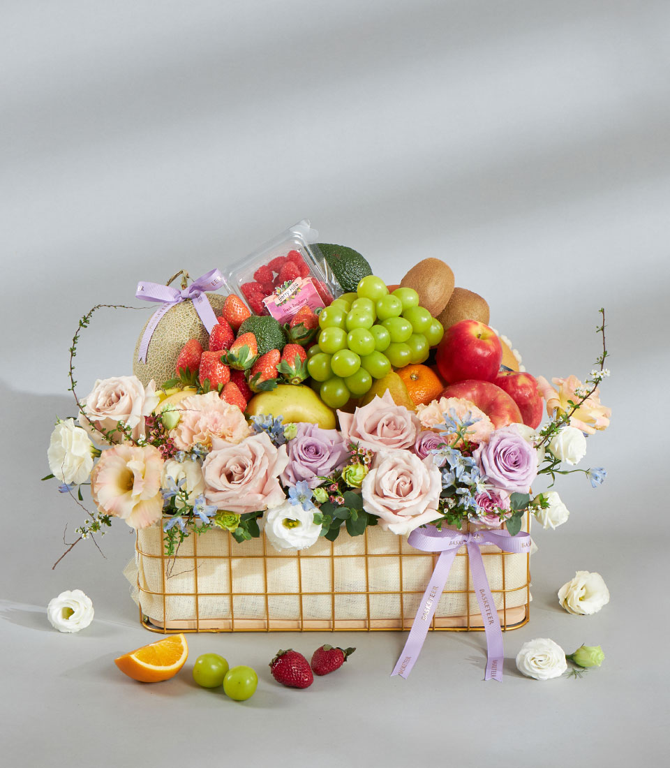 Pastel rose and fruit basket arrangement for gifting.