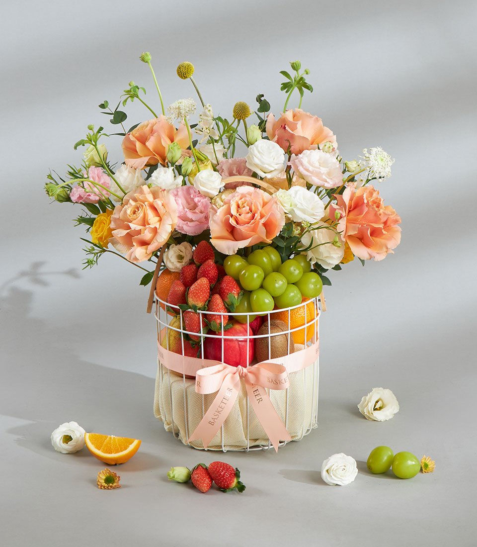 Healthy fresh fruit and pastel flower gift basket.