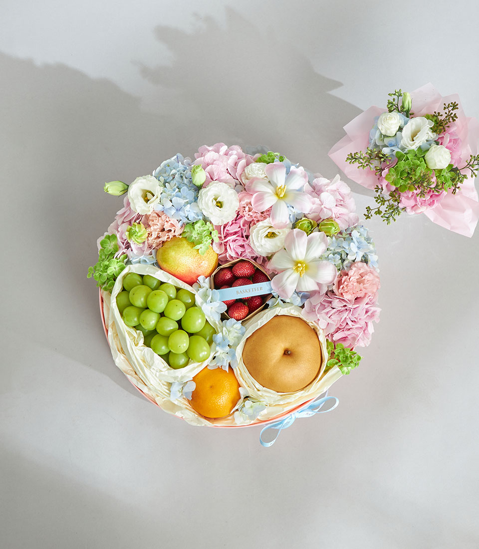 Gourmet pastel fruit and flower hatbox arrangement.
