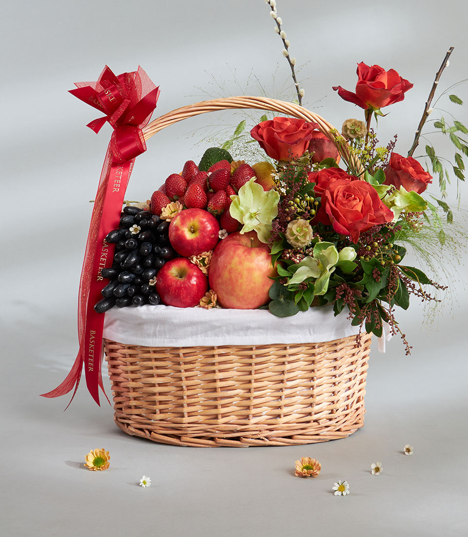 Healthy fresh fruit and red rose basket arrangement.