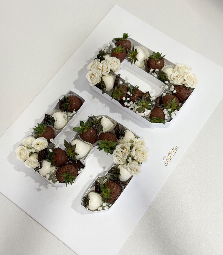 Number 50 cake decorated with chocolate strawberries and white roses by Charlotte Bakery