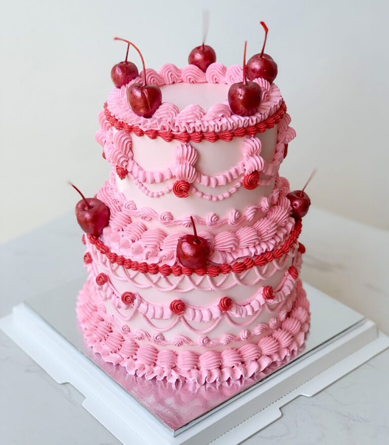 Pink vintage-style birthday cake with cherries and piped buttercream by Charlotte Bakery