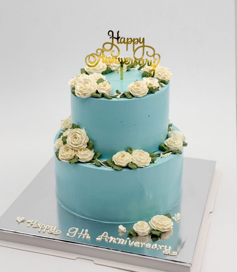 Charlotte Bakery blue wedding anniversary cake decorated with white buttercream roses and classic piping.