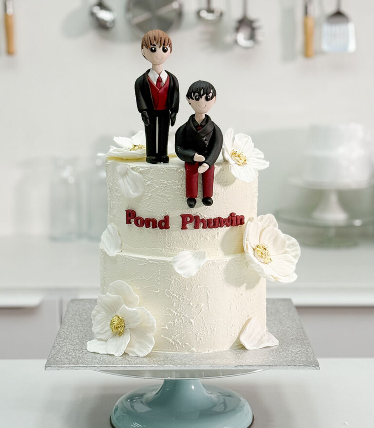 Charlotte Bakery custom wedding cake featuring handmade couple figurines and soft white buttercream details.
