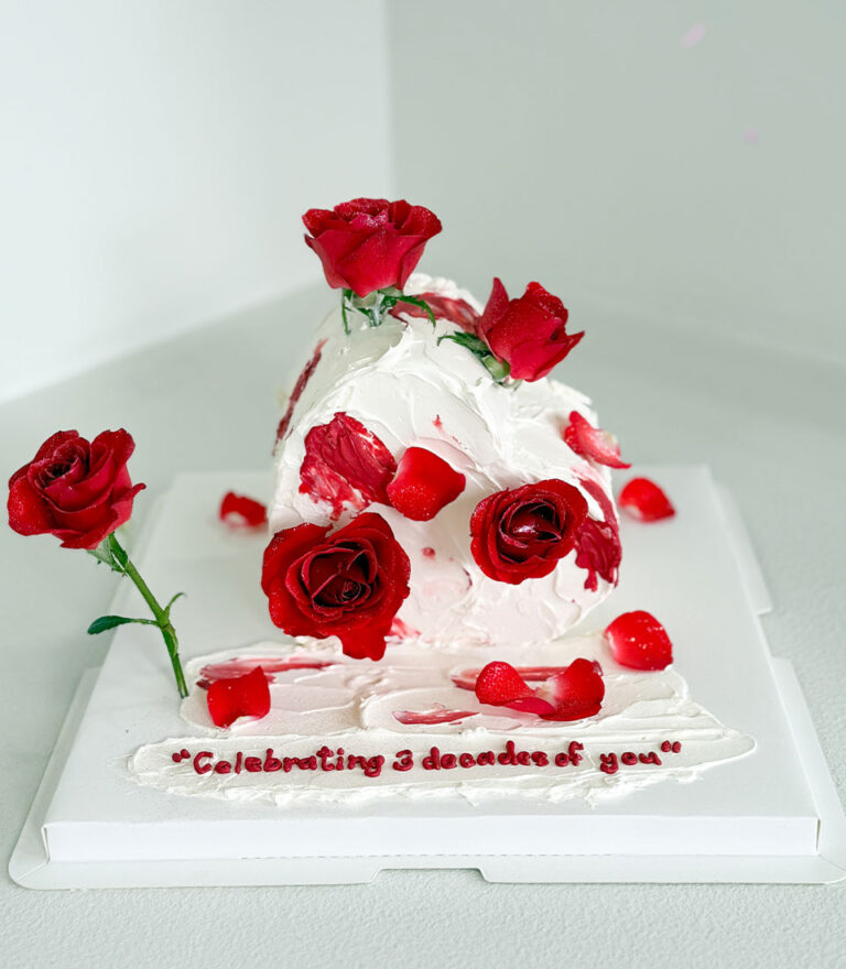 Charlotte Bakery anniversary cake decorated with red roses and textured white buttercream.