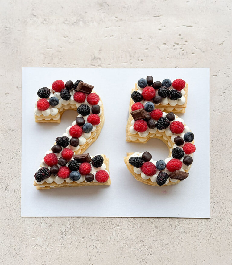 Elegant letter cake from Charlotte Bakery with clean cream finishing.