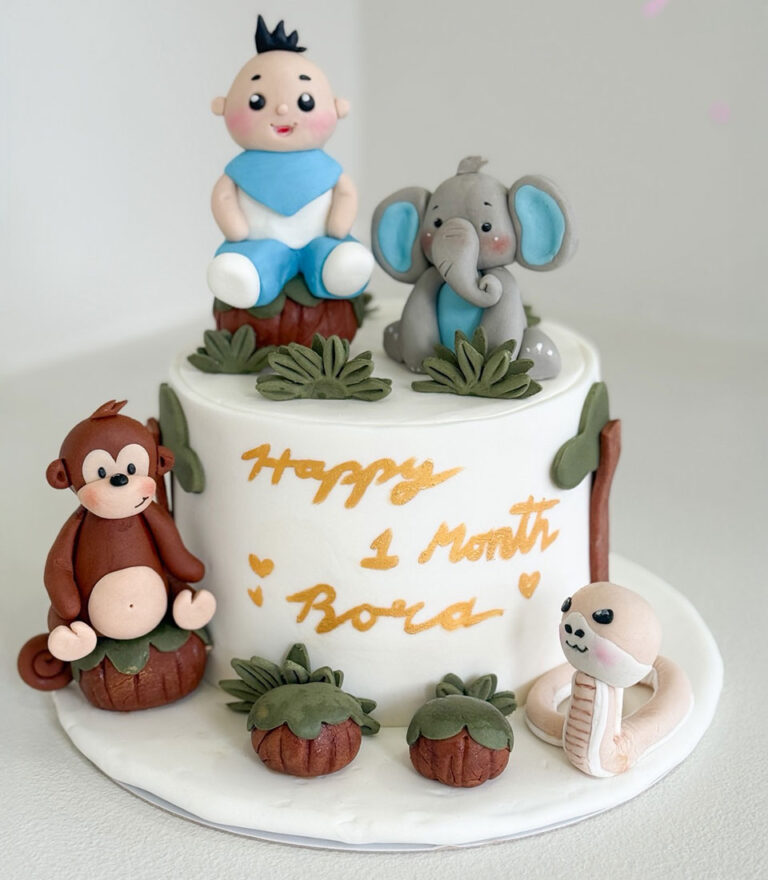 Jungle-themed fondant cake with baby and animal figures by Charlotte Bakery in Bangkok.