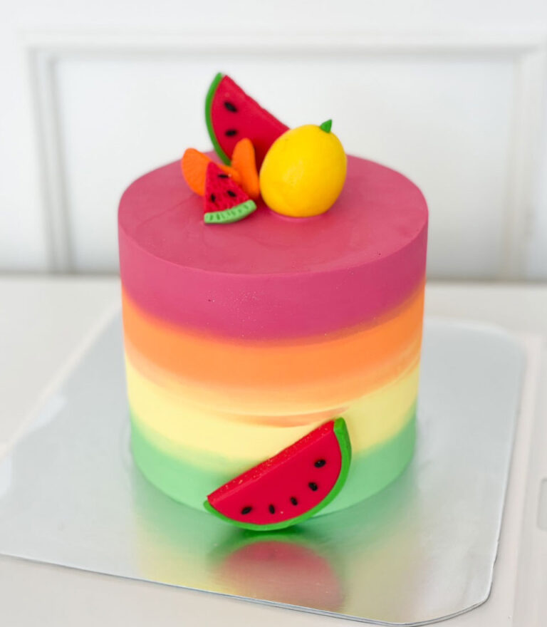 Rainbow-colored fondant cake topped with handcrafted fruit details by Charlotte Bakery in Bangkok.