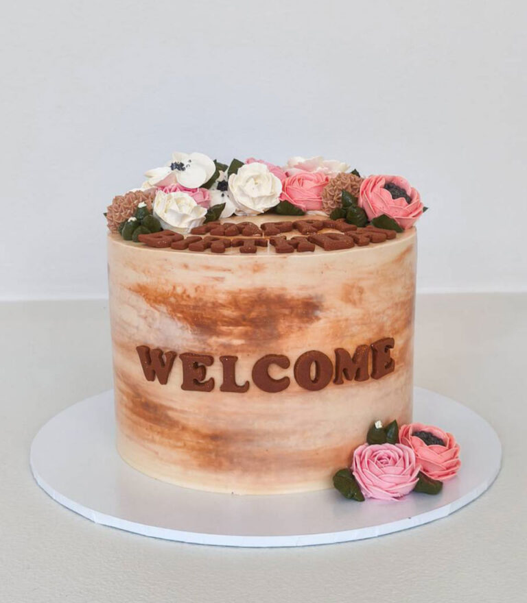 Rustic buttercream birthday cake with soft floral decorations and welcome lettering by Charlotte Bakery in Bangkok.