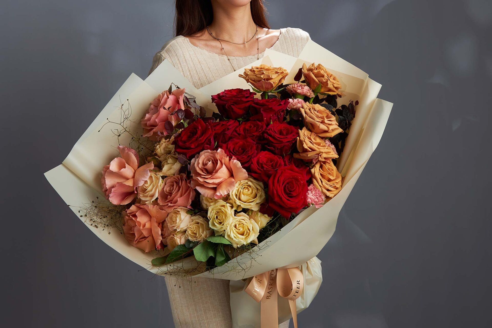 Premium flower bouquet delivery in Bangkok featuring red, peach, and cream roses arranged in an elegant hand-tied bouquet.