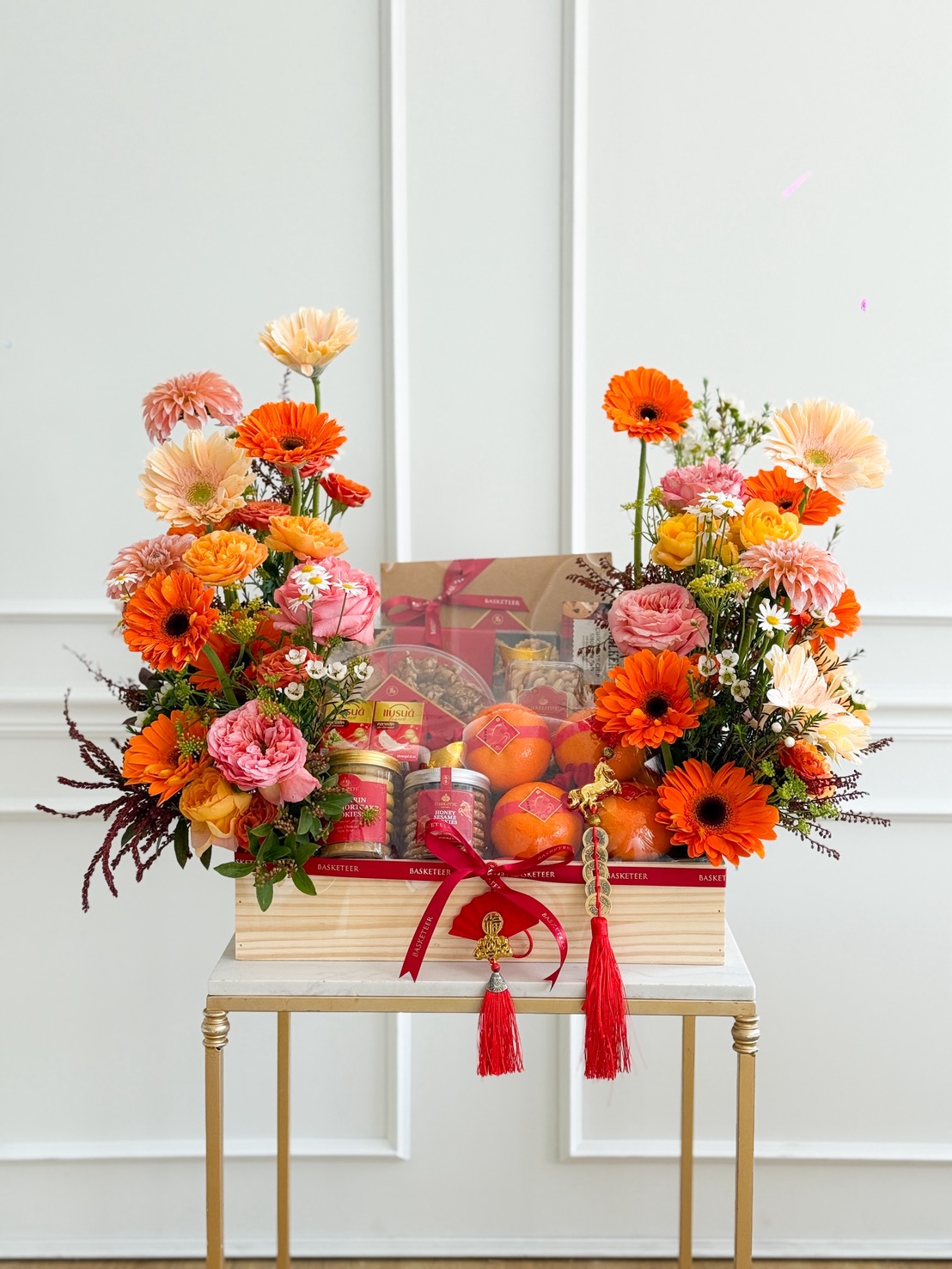 A Chinese New Year Luxury Gourmet & Wellness Hamper featuring a vibrant assortment of flowers and fresh oranges.
