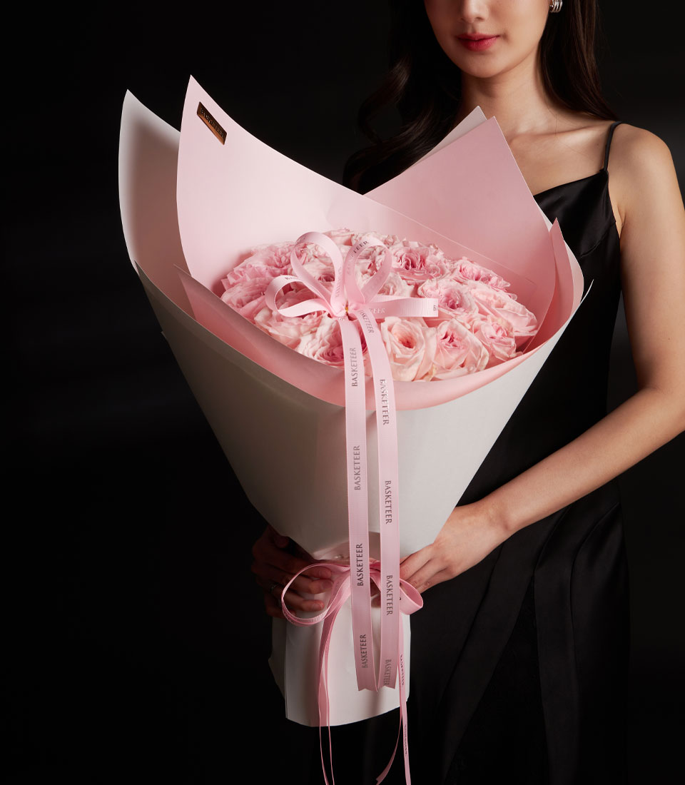 A large premium pink rose bouquet for Valentine gift delivery in Bangkok SKU VLT26-2020lModel holding a grand pink rose bouquet in layered pink and white wrappinglClose-up of fresh pink roses in a luxury Valentine arrangement with long pink ribbonslSide view of a large pink rose bouquet with branded Basketeer ribbon