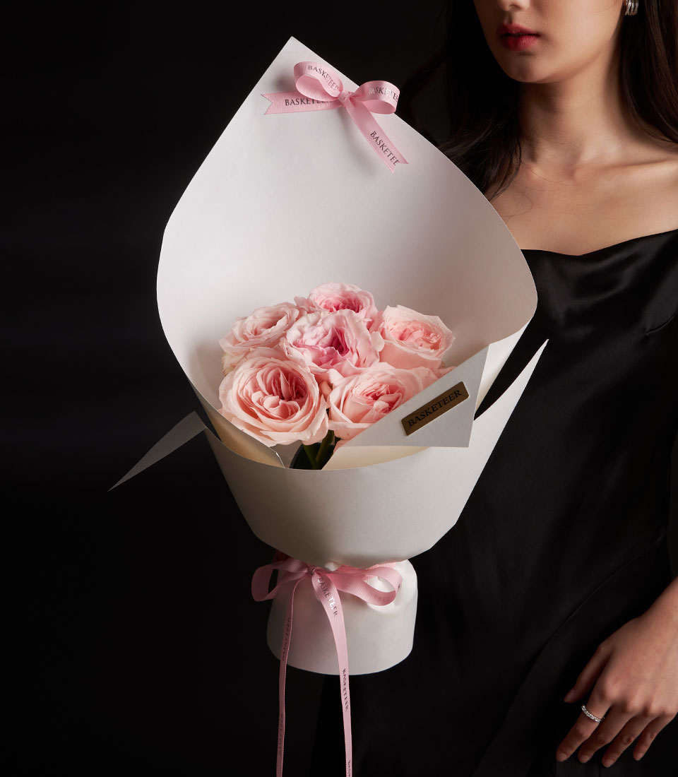 A sweet peach pink rose bouquet for Valentine gift delivery in Bangkok SKU VLT26-2024lFront view of a model holding a luxury pink rose bouquet in modern white sculptural wrappinglClose-up of fresh peach pink roses in a premium Valentine arrangement with pink ribbons