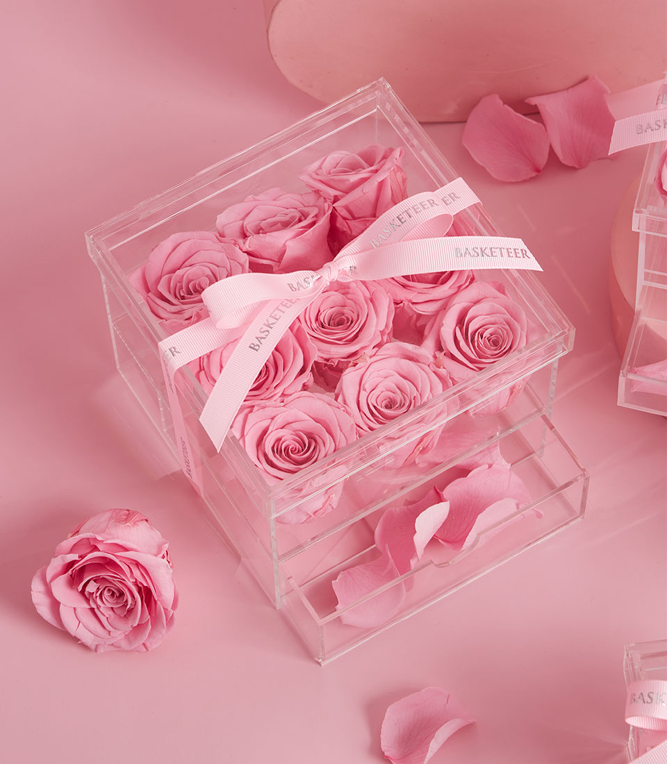 A Pink Preserved Roses Acrylic Box features neatly arranged blooms, tied with a white 