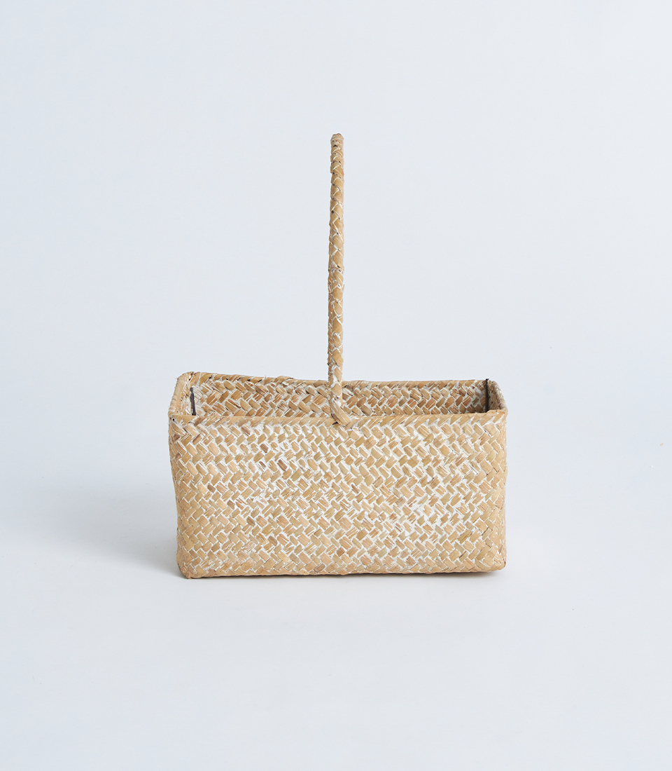 A front view of a rectangular natural straw basket featuring a clean elongated shape and a single curved handle, designed for minimal and elegant gift presentation in Bangkok delivery