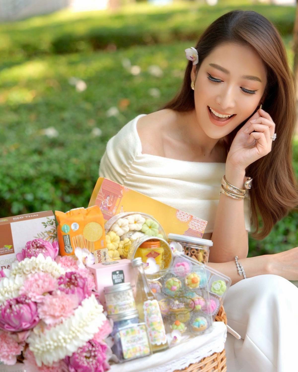 woman holding Songkran gift basket with lotus flowers and Thai desserts for Thai New Year gifting